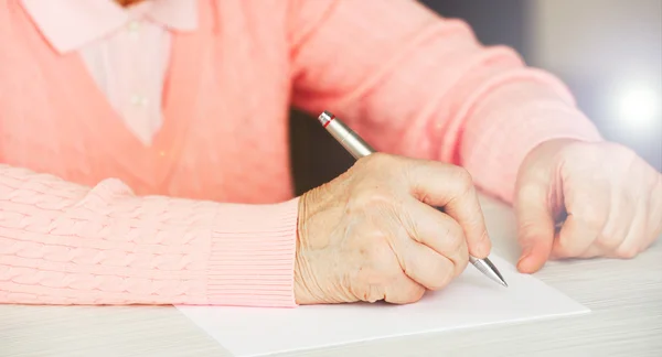 Manos de mujer adulta escribiendo con pluma en la mesa, primer plano — Foto de Stock