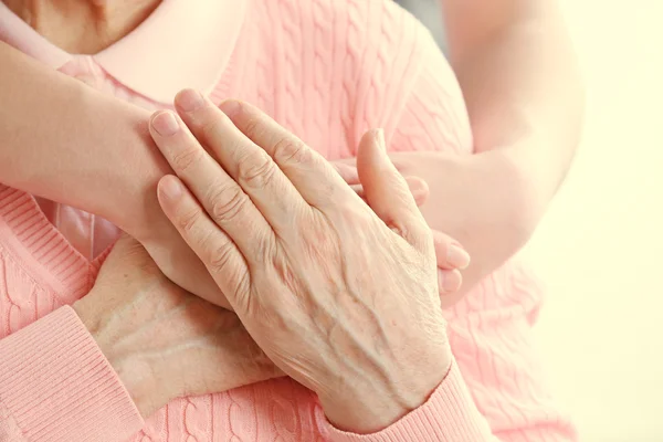 Old and young holding hands on light background, closeup — Stock Photo, Image