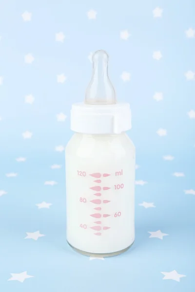 Baby bottle with milk on blue background — Stock Photo, Image