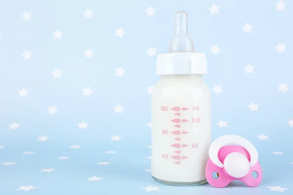 Baby milk bottle and pacifier on blue background — Stock Photo, Image