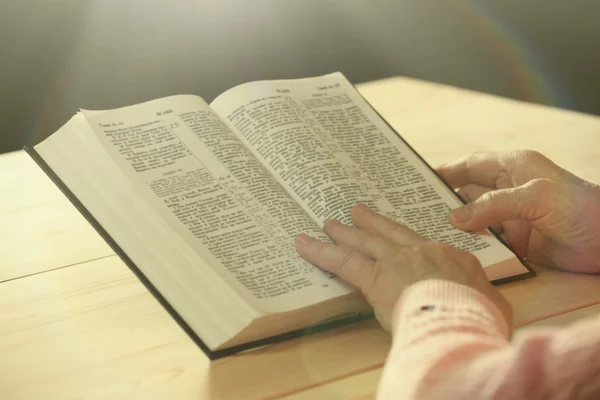 Hände einer alten Frau mit Bibel auf dem Tisch, Nahaufnahme Stockbild