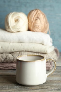 Ahşap arka plan üzerinde iplik ve giysileri örgü sıcak içecek fincan