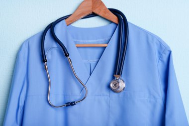 Askı üzerinde mavi arka plan üzerinde stetoskop ile doktor gömlek