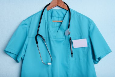 Askı üzerinde mavi arka plan üzerinde stetoskop ile doktor gömlek