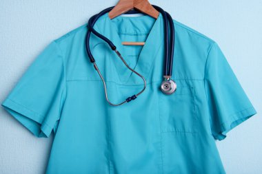 Askı üzerinde mavi arka plan üzerinde stetoskop ile doktor gömlek