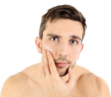 Yüzünde beyaz izole krem losyon uygulamak yakışıklı genç