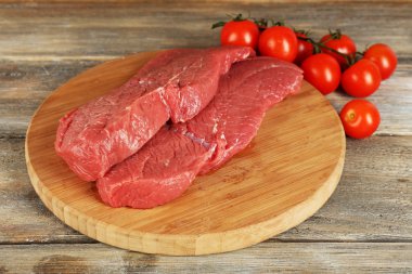 Kesme tahtası ahşap arka plan üzerinde kiraz domates ile ham sığır eti biftek