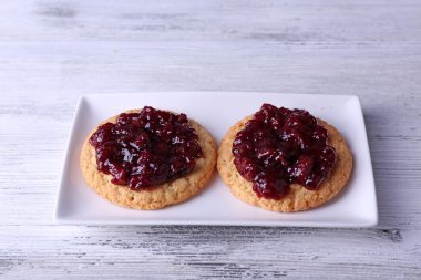 Ahşap arka plan üzerinde plaka üzerinde reçelli lezzetli kurabiyeler