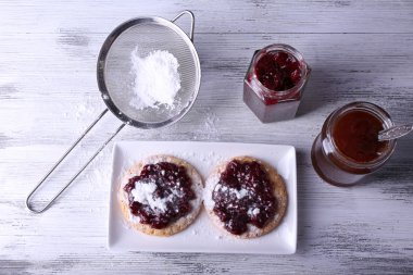 Reçel ve ahşap zemin üzerine tepside pudra şekeri ile lezzetli tatlılar