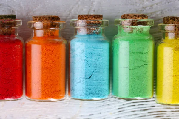 Bouteilles avec des pigments secs colorés sur fond en bois — Photo