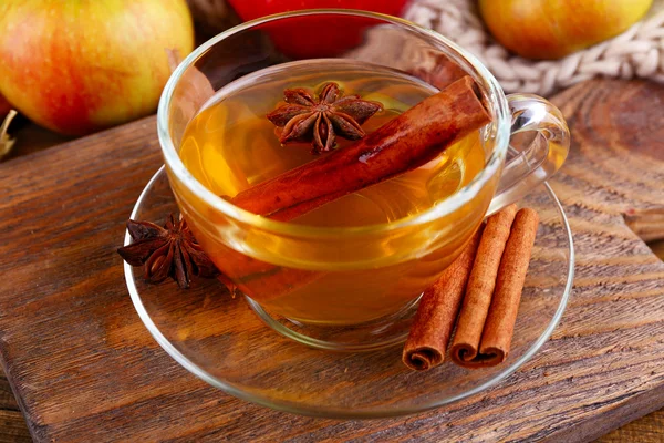Composition of  apple cider with cinnamon sticks, fresh apples, warm scarf and autumn leaves on wooden background — Stock Photo, Image