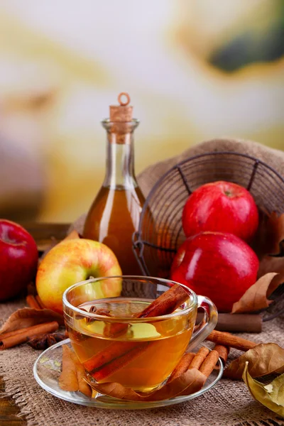 Composition of  apple cider with cinnamon sticks, fresh apples and autumn leaves on wooden background — Stock Photo, Image