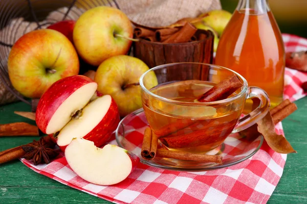 Composition of  apple cider with cinnamon sticks, fresh apples and autumn leaves on wooden background — Stock Photo, Image