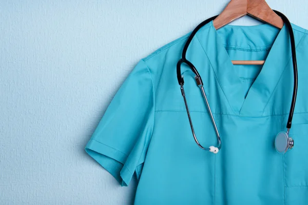 Camisa médica con estetoscopio en percha sobre fondo azul —  Fotos de Stock