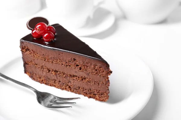 Köstlicher Schokoladenkuchen auf Teller auf Tisch vor hellem Hintergrund — Stockfoto