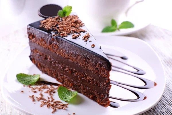 Delicioso bolo de chocolate na placa na mesa no fundo claro — Fotografia de Stock