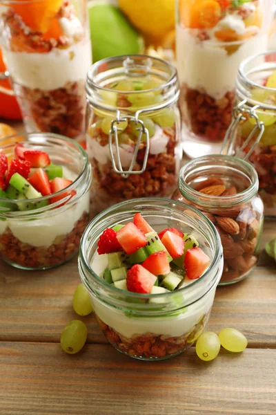 Sobremesas em camadas saudáveis com muesli e frutas na mesa — Fotografia de Stock