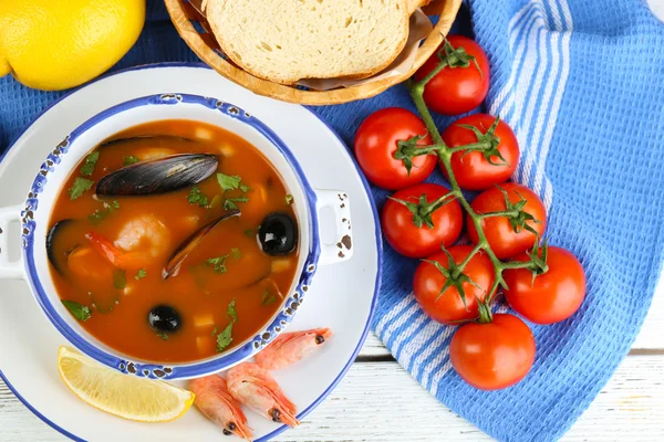 Sopa saborosa com camarões, mexilhões, tomates e azeitonas pretas em tigela sobre fundo de madeira — Fotografia de Stock