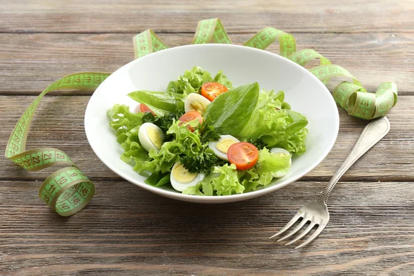 Salad with quail egg and basil in plate on rustic wooden table background — Stock Photo, Image