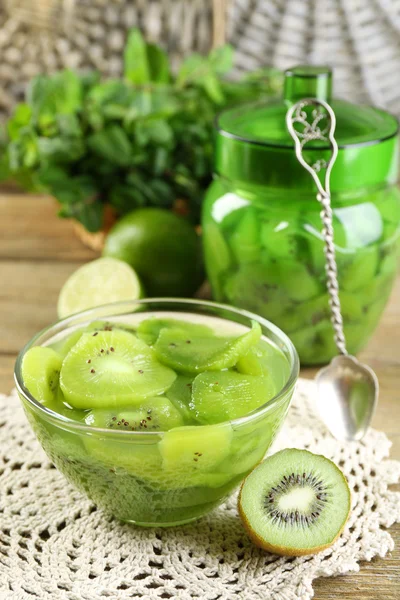 Välsmakande kiwi jam i skål och burken på trä bakgrund — Stockfoto