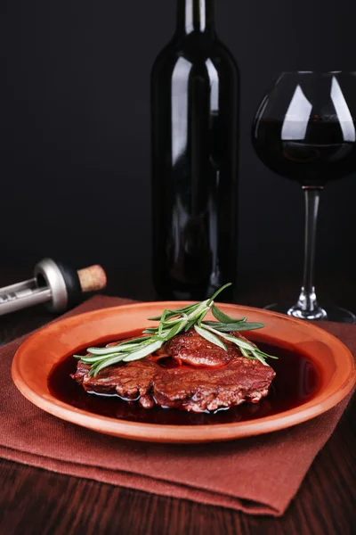 Bife grelhado em molho de vinho com copo de vinho no fundo escuro — Fotografia de Stock