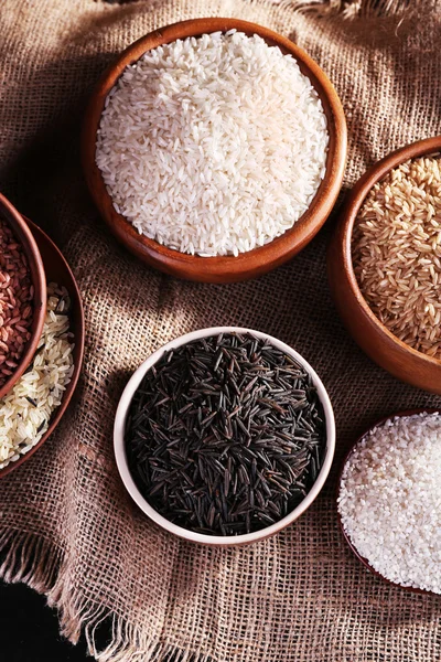 Различные виды риса в мисках на мешковине фоне — стоковое фото