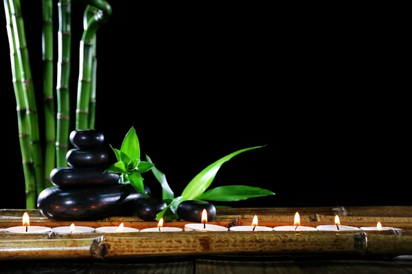 Schöne Komposition mit Wellness-Steinen und Kerzen auf Tisch auf dunklem Hintergrund — Stockfoto