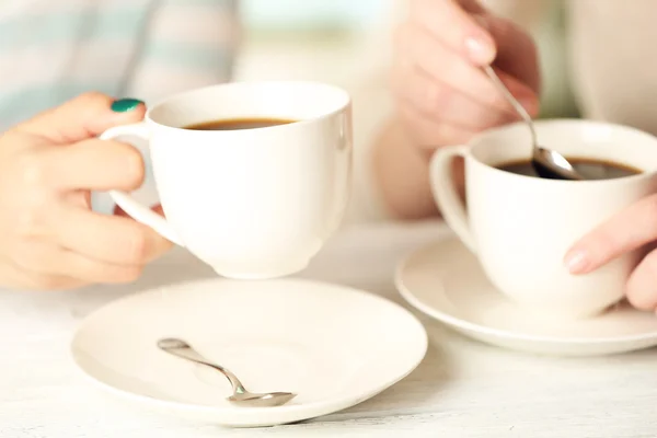 Dos mujeres con tazas de café sobre fondo brillante — Foto de Stock