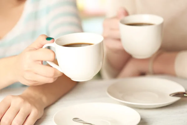 Dos mujeres con tazas de café sobre fondo brillante — Foto de Stock