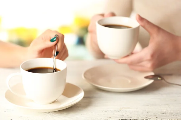 Twee vrouwen met kopjes koffie op lichte achtergrond — Stockfoto