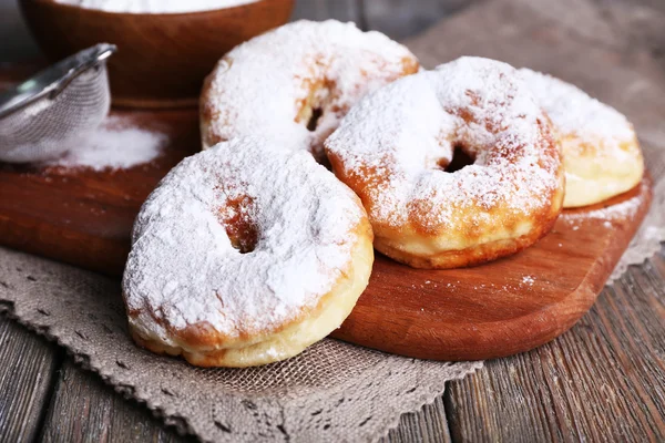 Delicious donuts with icing and powdered sugar on wooden background — Stock Photo, Image