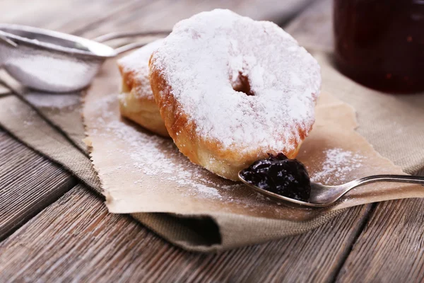 Deliciosos donuts com cobertura e açúcar em pó no fundo de madeira — Fotografia de Stock