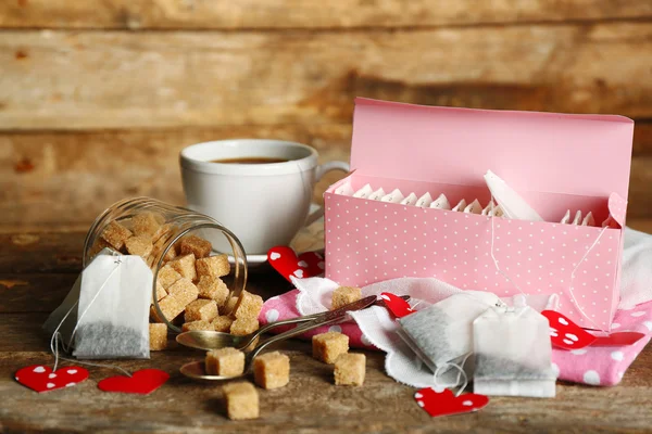 Heart shaped teabag tags and Cup of tea with on wooden background — Stock Photo, Image