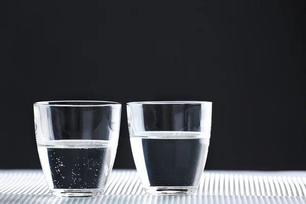 Zwei Gläser Wasser auf dem Tisch auf dunklem Hintergrund — Stockfoto