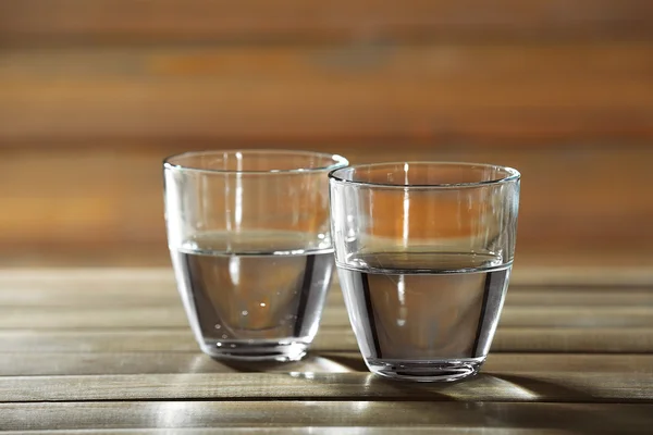 Два стакана воды на столе на деревянном фоне — стоковое фото