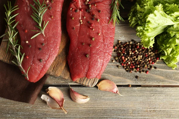 Raw beef steak with spices and greens on table close up — Stock Photo, Image