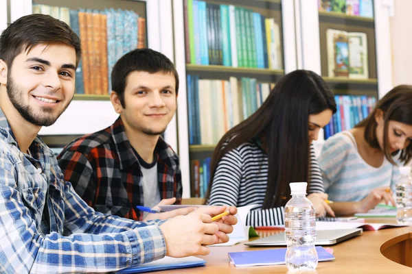 Bir grup öğrenci kütüphanede masada oturuyor. — Stok fotoğraf