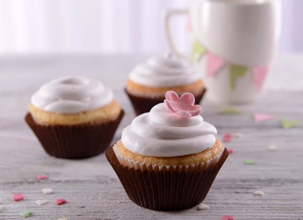 Deliciosos cupcakes en la mesa sobre fondo claro — Foto de Stock