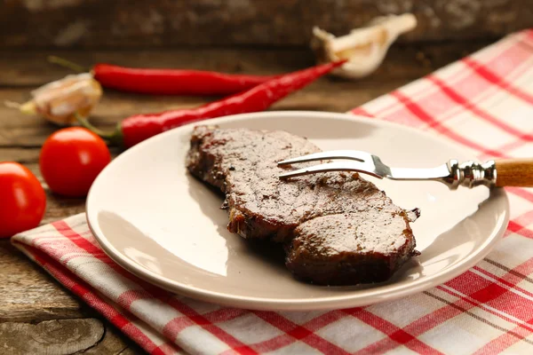 Composizione con gustosa carne arrosto su piatto, verdure su fondo di legno — Foto Stock