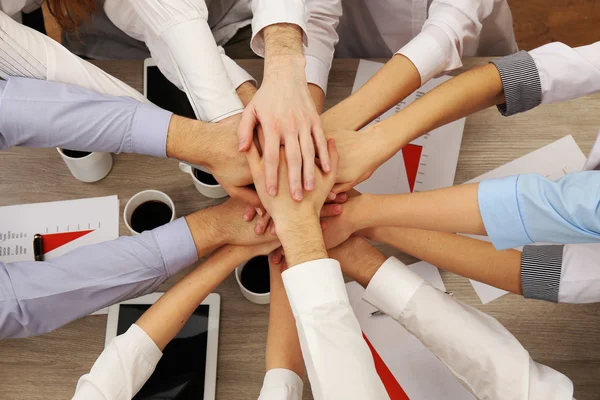 Verenigd handen van zakelijke team op werkruimte achtergrond bovenaanzicht — Stockfoto