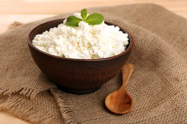 Cottage cheese in bowl on sackcloth background — Stock Photo, Image