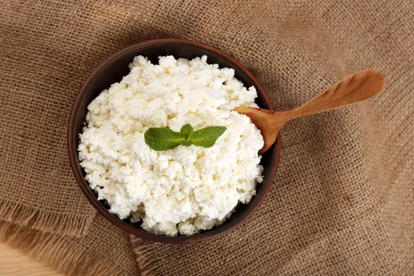 Cottage cheese in bowl on sackcloth background — Stock Photo, Image