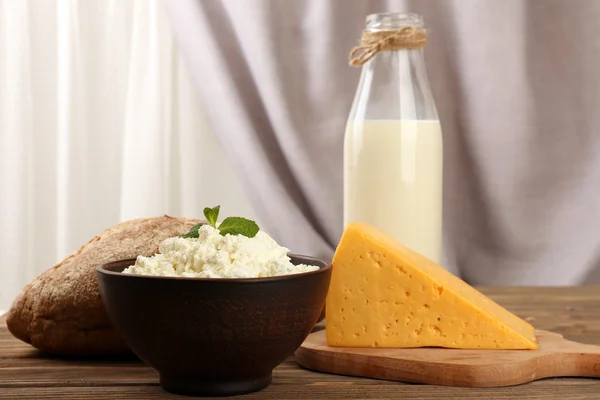 Productos lácteos sabrosos con pan en la mesa sobre fondo de tela —  Fotos de Stock