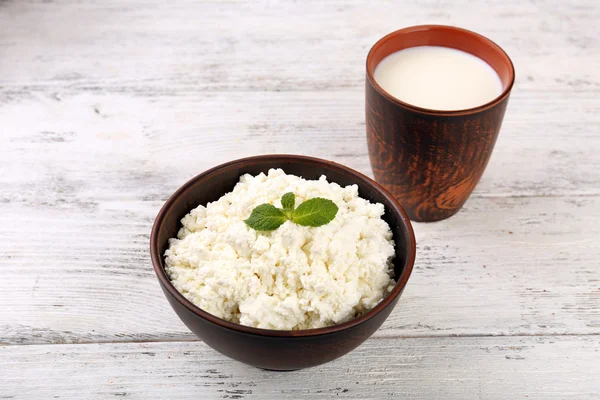 Cottage cheese in bowl with cup of milk on wooden background — Stock Photo, Image