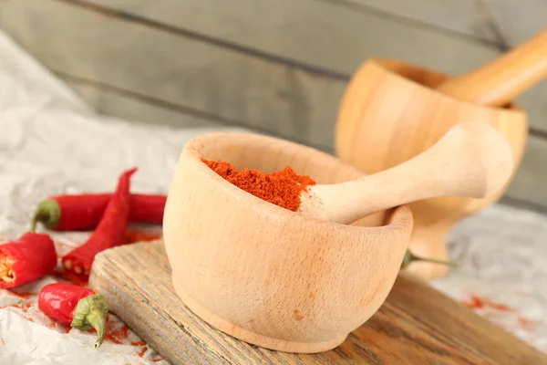 Ground red pepper in mortar with chili pepper on wooden background — Stock Photo, Image