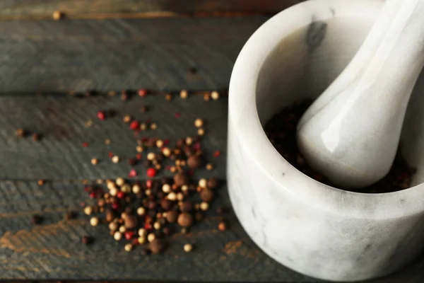 Mixture of peppers in mortar on wooden background — Stock Photo, Image