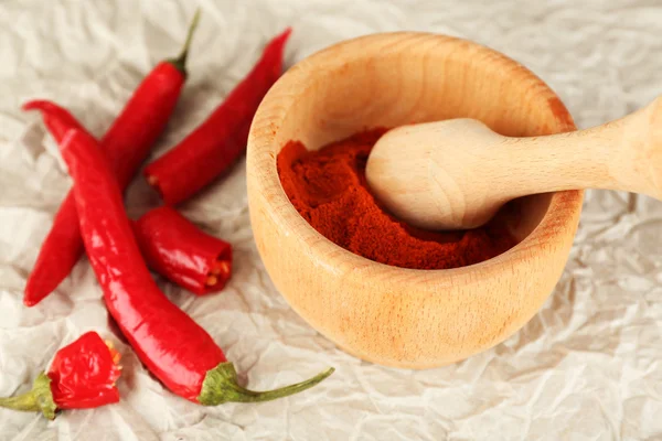 Ground red pepper in mortar with chili pepper on table close up — Stock Photo, Image