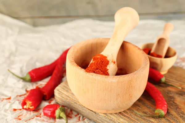 Ground red pepper in mortar with chili pepper on wooden background — Stock Photo, Image