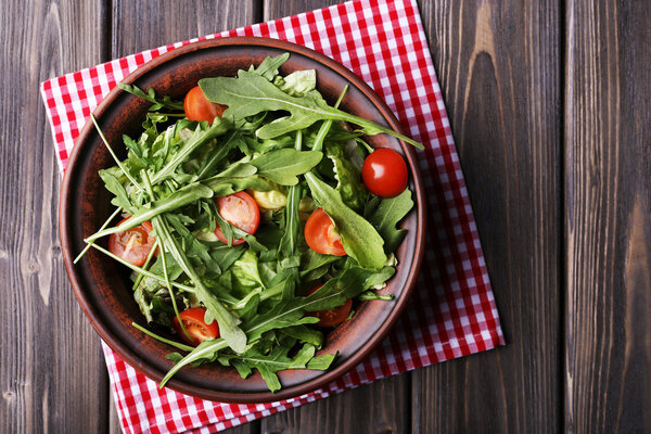 Salad with arugula and cherry tomatoes on wooden table