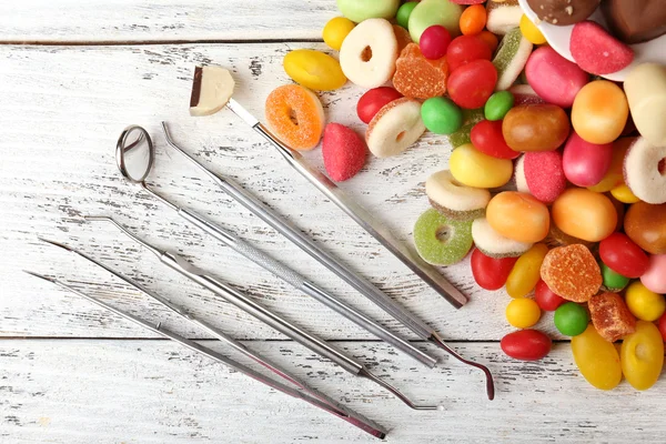 Dentist tools with sweets on wooden background — Stock Photo, Image